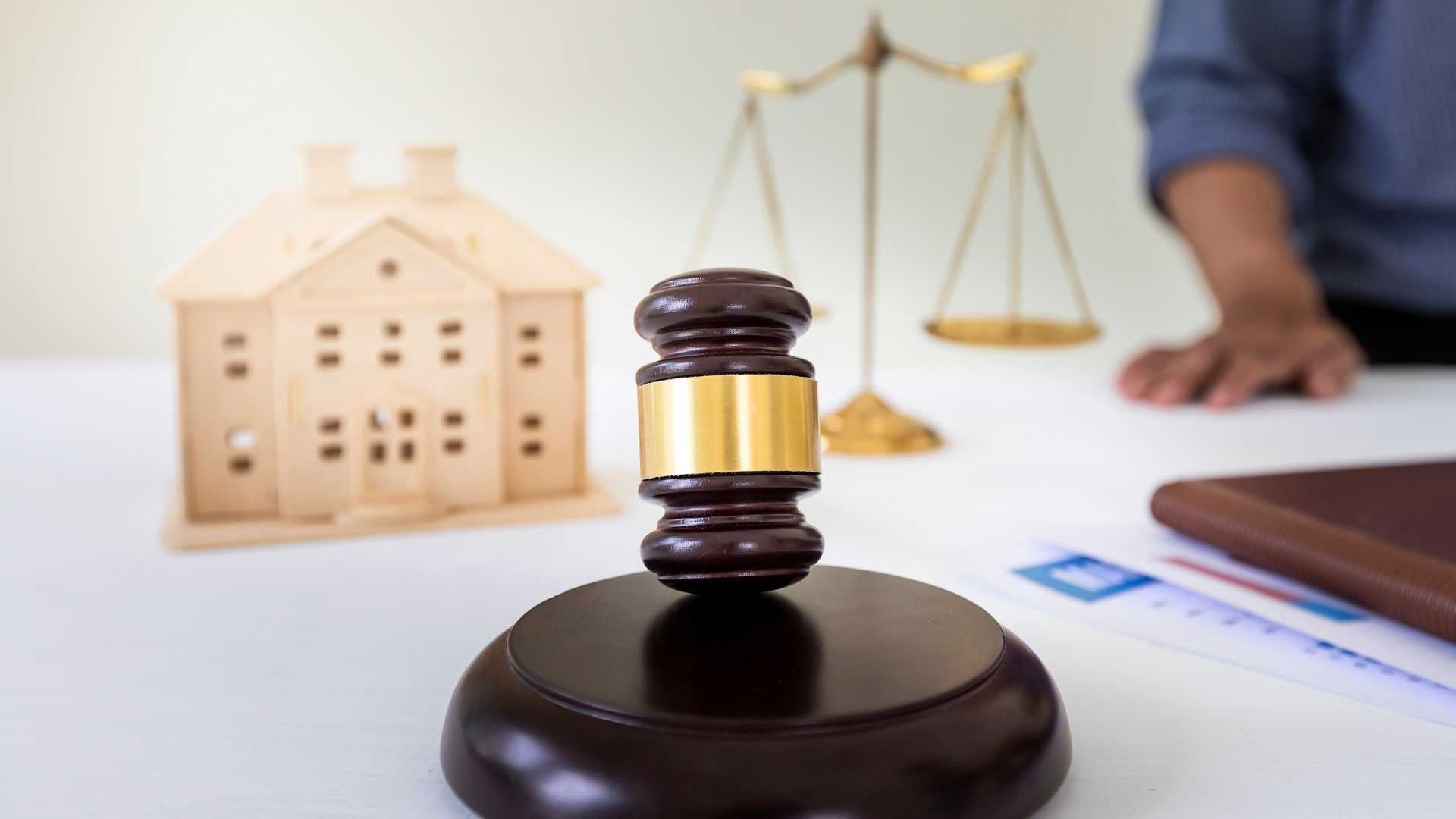 judges gavel on a desk with a scale and model of a house